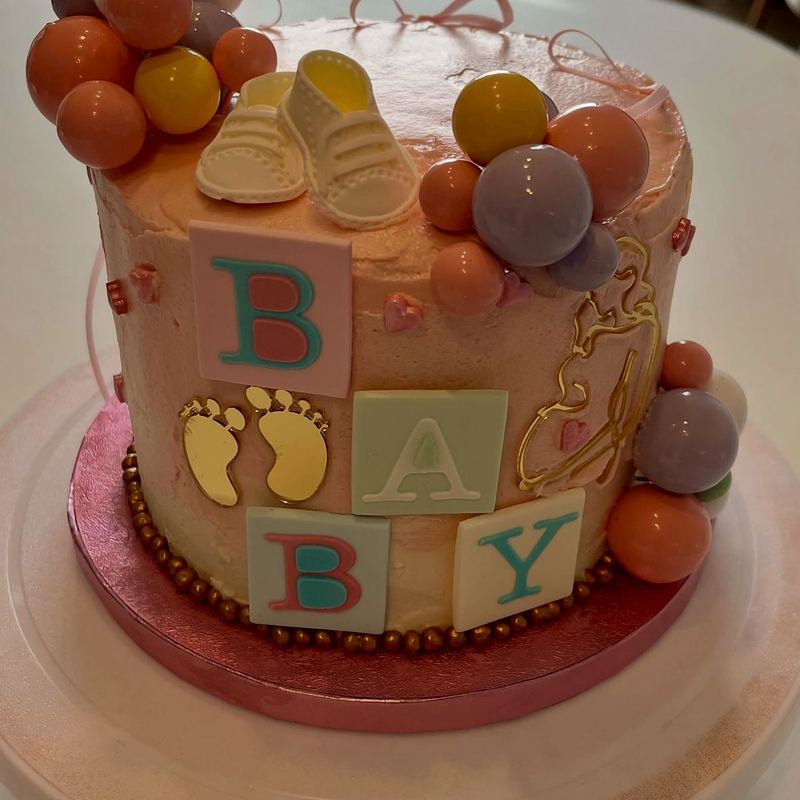 Baby shower cake with lettered blocks and pastel spheres