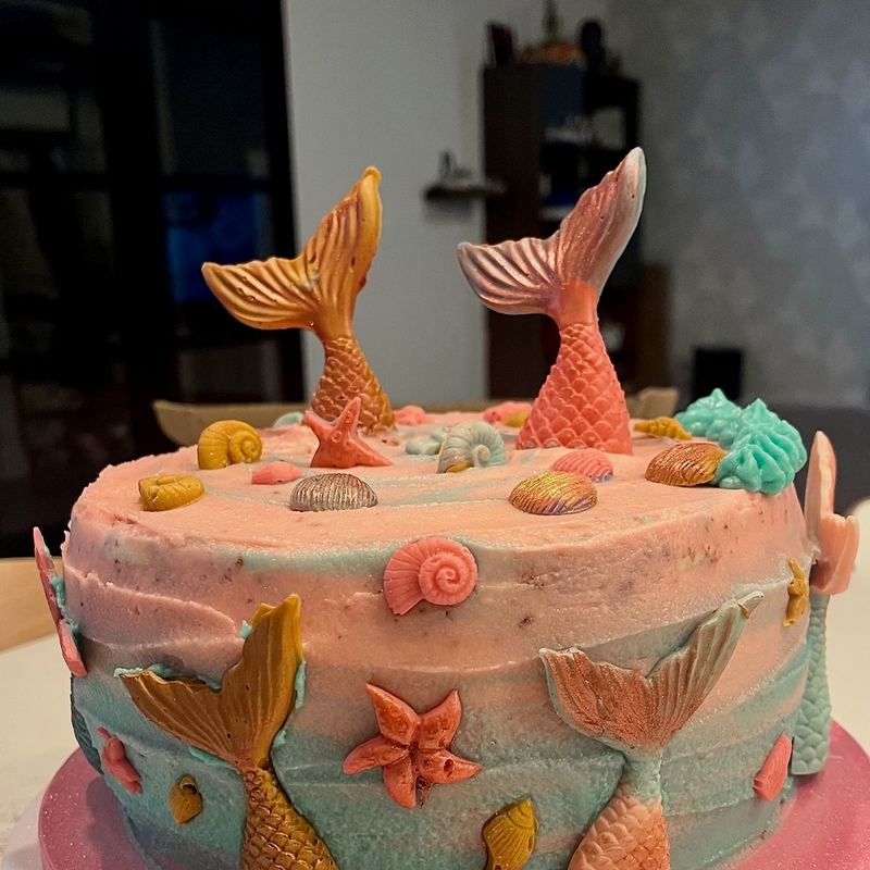 Ocean-themed cake with mermaid tails and shells